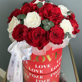 Red and white roses in a red heart-themed box with a white ribbon