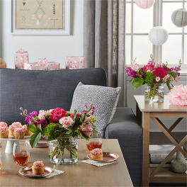 Pink and magenta flower arrangements in glass vases on a living room table