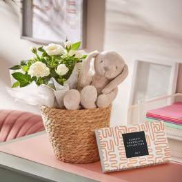 White rose bouquet in a woven basket with a plush bunny and chocolate box