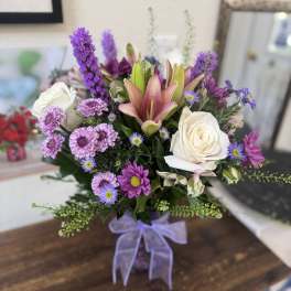 Bouquet of pink lilies, white roses, and purple daisies in a vase