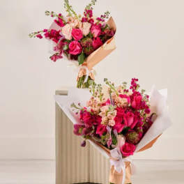 Two pink and peach flower bouquets wrapped in paper