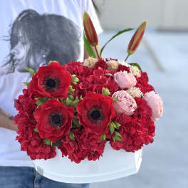 Red and pink flower arrangement in a white box