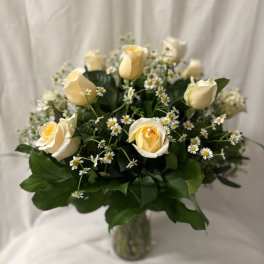 Cream roses and small white daisies in a glass vase
