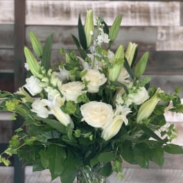 White roses and lilies arranged in a clear glass vase
