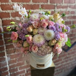 Pastel bouquet of roses, dahlias, and orchids in a white hatbox