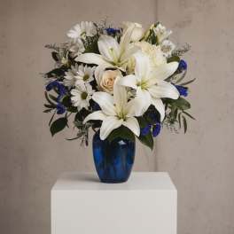White lilies and daisies arranged in a blue vase