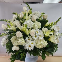 White roses, lilies, daisies, and hydrangeas in a white vase