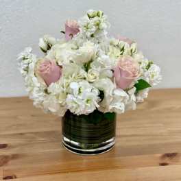 Pink roses and white flowers arranged in a glass vase