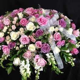 Large arrangement of pink, purple, and white roses with ribbon