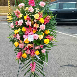 Standing floral spray with pink, yellow, and white flowers on an easel
