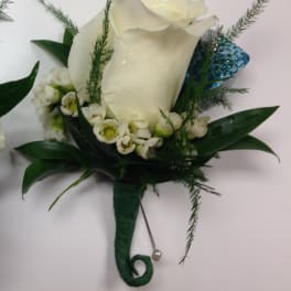 White rose boutonniere with small white blossoms, greenery, and a blue glitter accent wrapped with a pearl pin