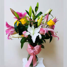 Bouquet of pink and white lilies with yellow roses in a glass vase