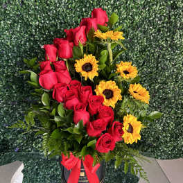 Red roses and yellow sunflowers in a black hatbox with a red ribbon