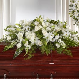 White floral casket spray with lilies, roses, and daisies