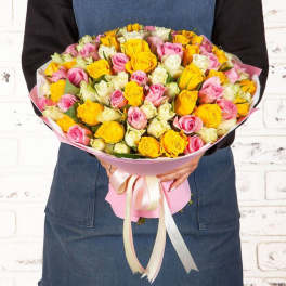 Bouquet of pink, yellow, and white roses wrapped in pink paper