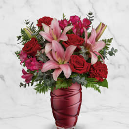 Pink lilies and red roses arranged in a red vase