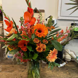 Orange mixed bouquet in a clear glass vase