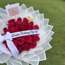 Bouquet of red roses with a birthday ribbon and white wrap