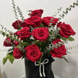 Red roses arranged in a black hatbox with a ribbon