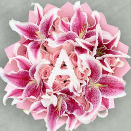 Pink lilies and roses arranged in a bouquet with pink wrapping