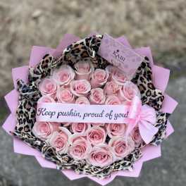 Pink rose bouquet wrapped in leopard-print paper with a ribbon banner