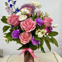 Pink and white mixed bouquet in a pink glass vase with a ribbon