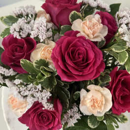 Bouquet of hot pink and peach roses with small white filler flowers