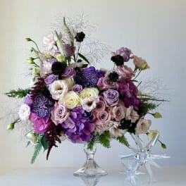 Lavender and pink floral arrangement in a clear glass pedestal vase