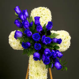 Standing white chrysanthemum cross with cluster of vivid blue roses on a wooden easel