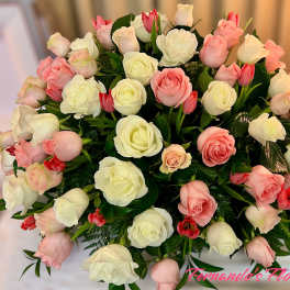 Large dome of white and blush pink roses with small red tulips in a rounded arrangement