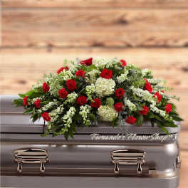 Red and white casket spray with roses, carnations, hydrangeas, and trailing white blooms on a silver casket