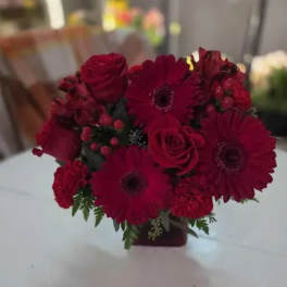 Red roses and gerbera daisies arranged in a small vase
