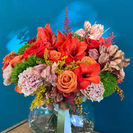Bouquet of red and peach flowers in a clear glass vase