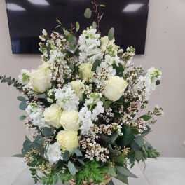 Tall basket arrangement of white roses and white blooms with small blush accents