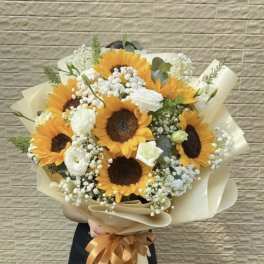 Bouquet of sunflowers and white blooms wrapped in cream paper