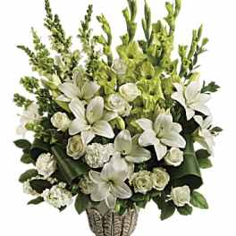 Tall white lily and rose arrangement with green accents in an ornate pedestal vase