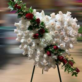 Heart-shaped standing spray of ivory roses with red roses accent on a metal easel.