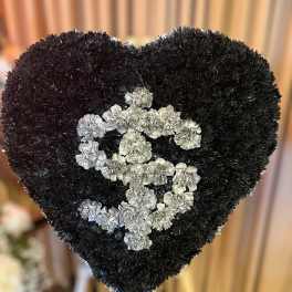 Heart-shaped black floral standing spray with silver carnations forming a dollar sign.