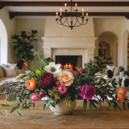 Mixed rose arrangement in a low ceramic vase on a wooden table