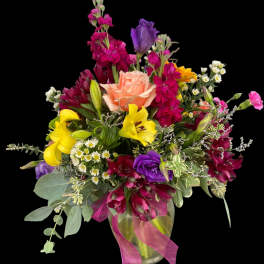 Mixed bouquet with roses, lilies, and purple blooms in a glass vase