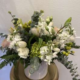 White floral arrangement in a vase with eucalyptus and green berries