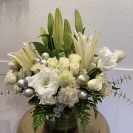 White lilies and roses arranged in a dark vase with silver accents
