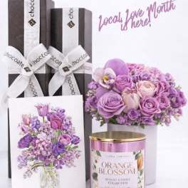 Gift set with purple flowers, chocolate boxes, and a pink candle