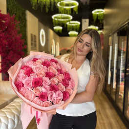 Woman holding a large bouquet of pink roses wrapped in pale pink paper