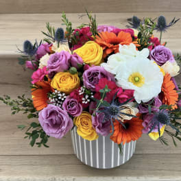 Colorful bouquet of roses, gerbera daisies, and a white anemone in a striped vase
