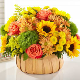 Mixed bouquet in a wooden basket with sunflowers and roses