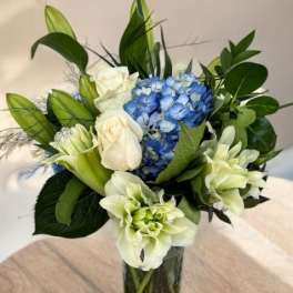Blue hydrangeas and white roses in a clear glass vase
