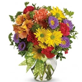 Colorful mixed bouquet in a clear glass vase with a green polka-dot ribbon