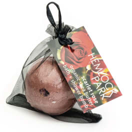 Wrapped bath bomb in a black mesh pouch with a rose-themed tag