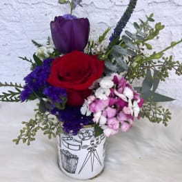 Red rose and purple tulip arrangement in a printed ceramic vase